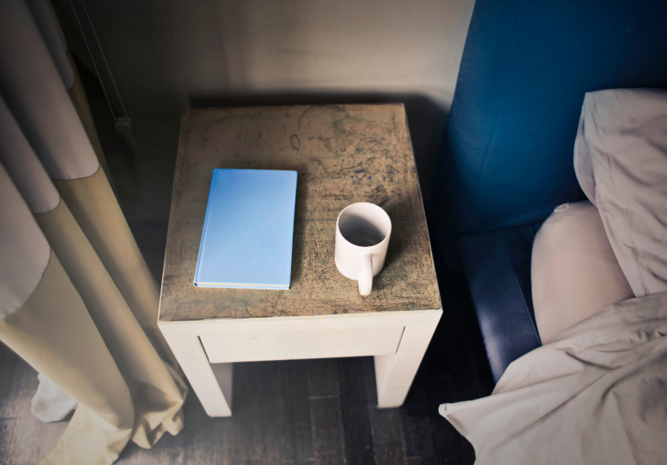 Una taza y un libro en la mesa de luz